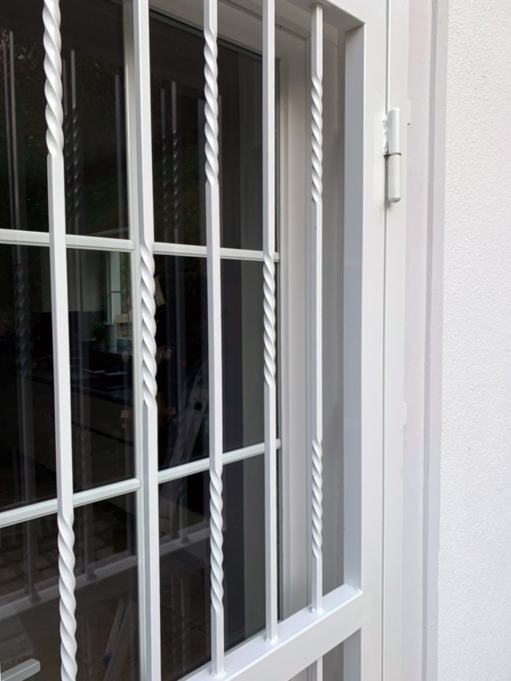 Weiß pulverbeschichtete Gittertür als zusätzlicher Einbruchschutz – gefertigt und montiert von Andreas Koegler Alarmanlagen Wien